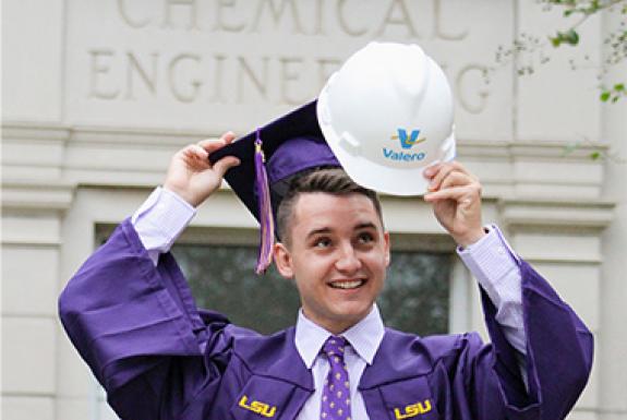 Man taking off graduation cap and putting on Valero hard helmet
